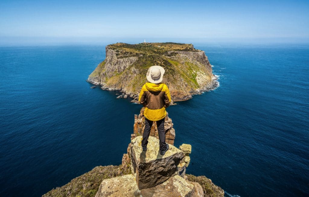 a person on the edge of a cliff in tasmania