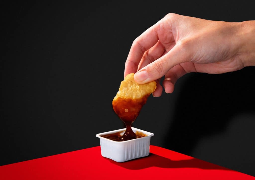 Someone dipping a nugget into sauce