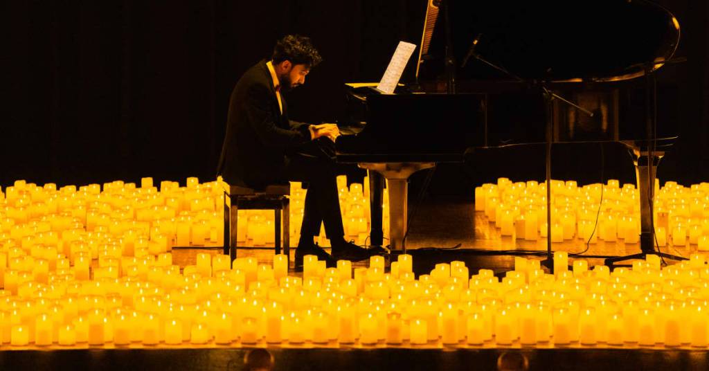 A pianist performing amid a sea of candles