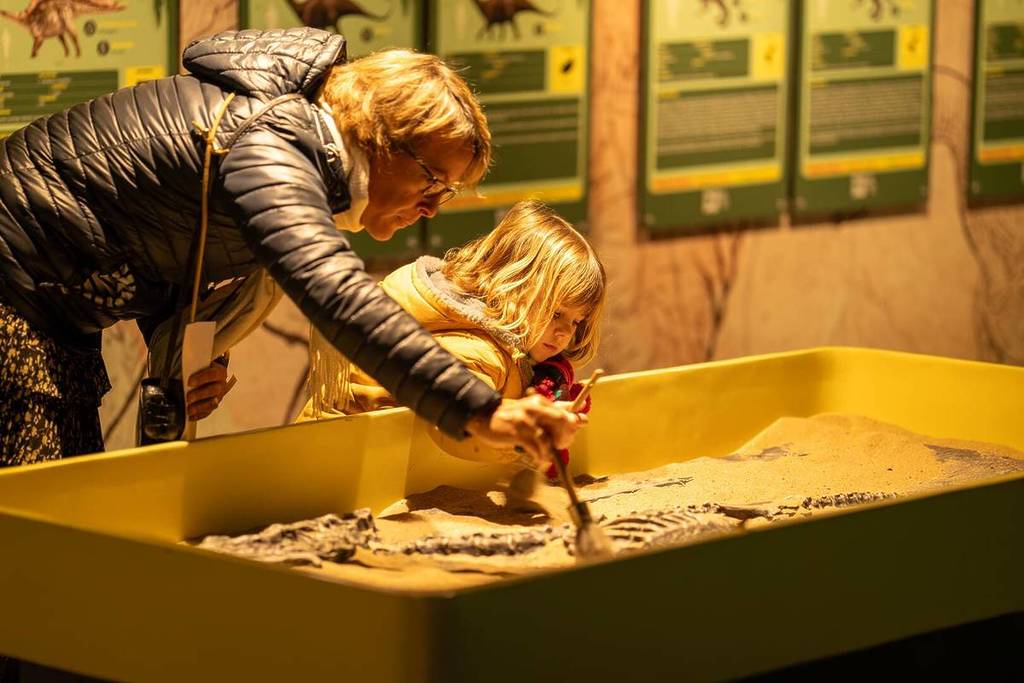 A mother and her young daughter search for fossils in a sand pit at Dinos Alive.