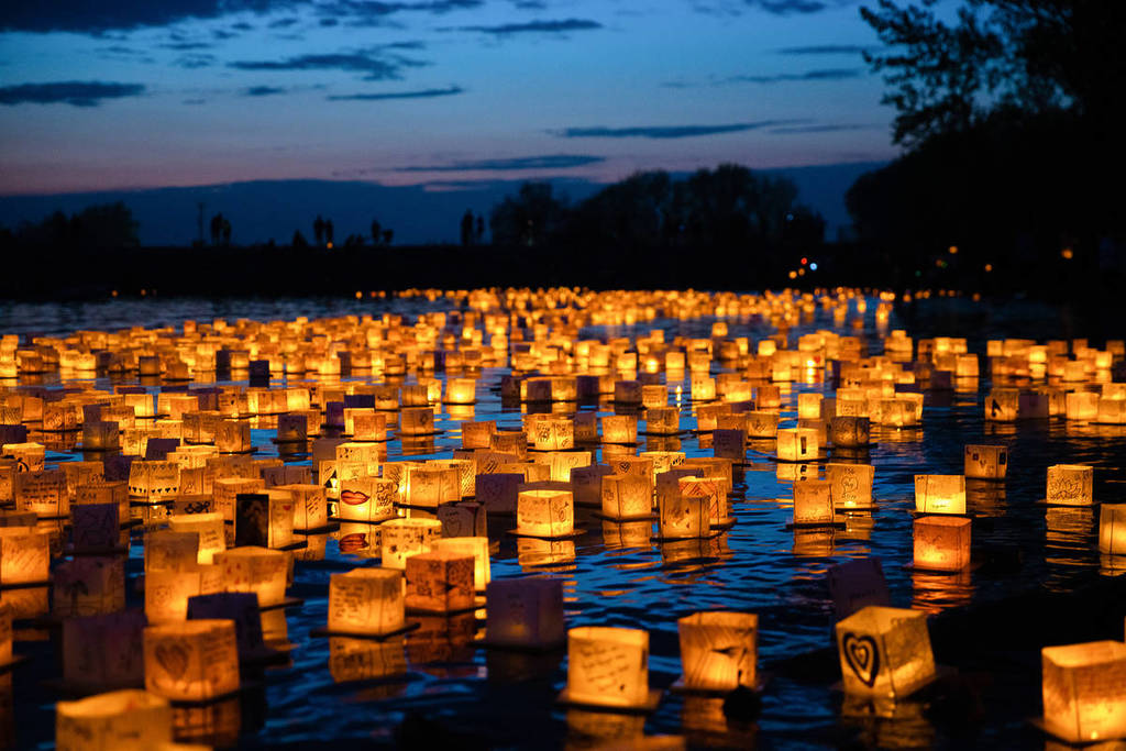 Hundreds of glowing lanterns float on the water at night at the Water Lantern Festival.