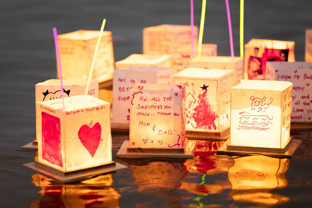 A close-up shot of personalised lanterns with drawings and messages floating on the water at the Water Lantern Festival.