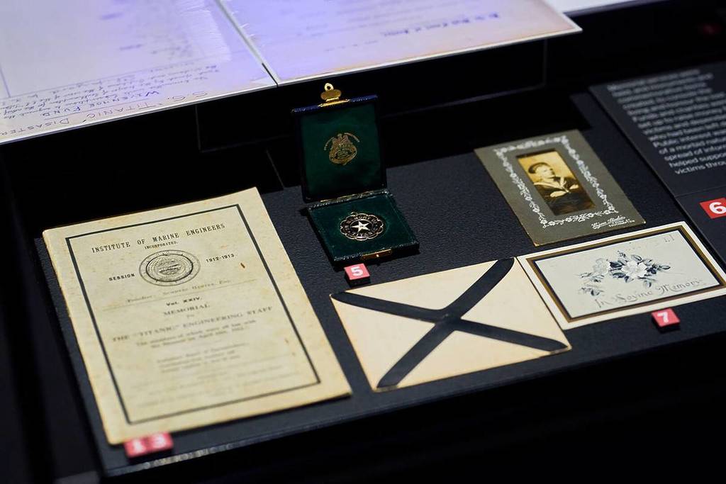 A close-up shot of a medal, letter and personal documents of a passenger aboard the Titanic at Titanic. The Human Story.