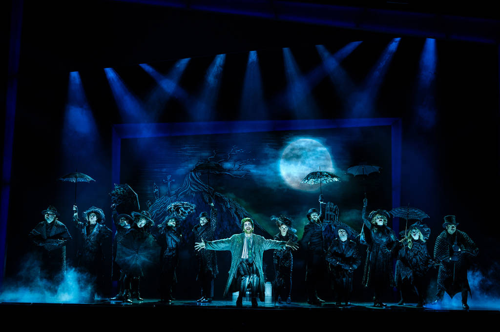 the image shows a snippet from Beetlejuice The Musical with the main character surrounded by a few dozen actors in a musical number.