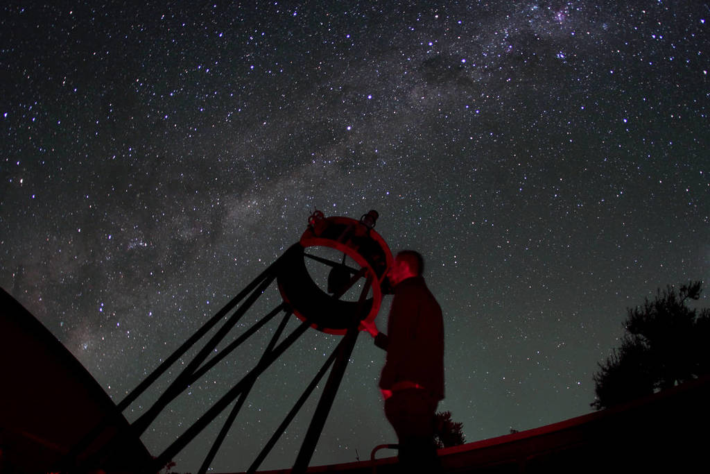 The image features the night sky, lit up by stars with a man standing underneath from an ant's point of view.