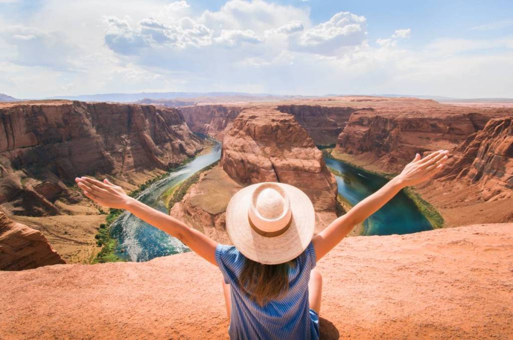 woman sits infront of canyon with her arms stretched out
