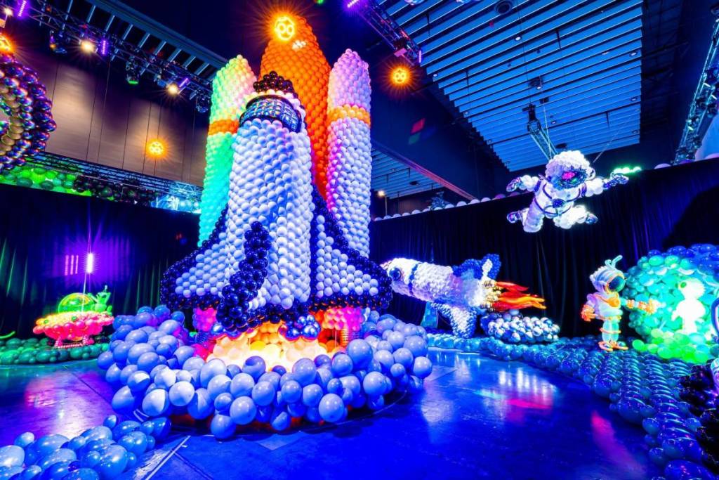 A colourful balloon sculpture of a massive rocketship surrounded by planets, astronauts, UFOs and aliens at Balloon Story.