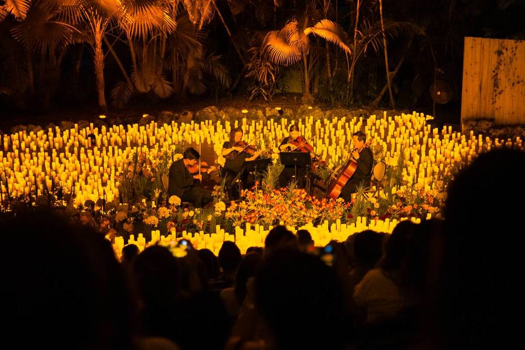 A string quartet performing amid a sea of candles and flowers