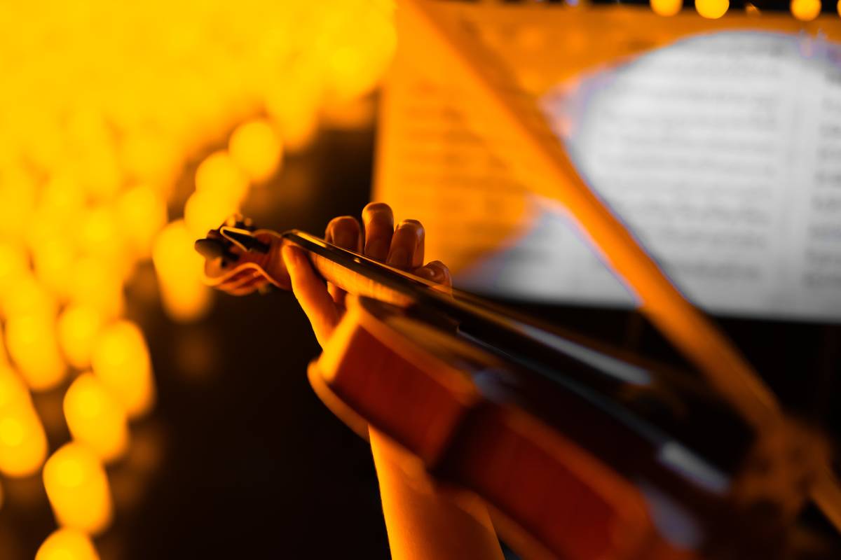 Primo piano di un violino ed uno spartito circondati da candele