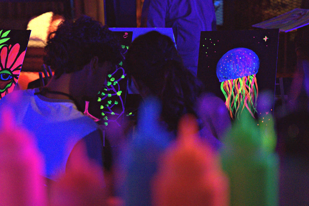 Le spalle di due persone che guardano i loro quadri al Neon Brush.