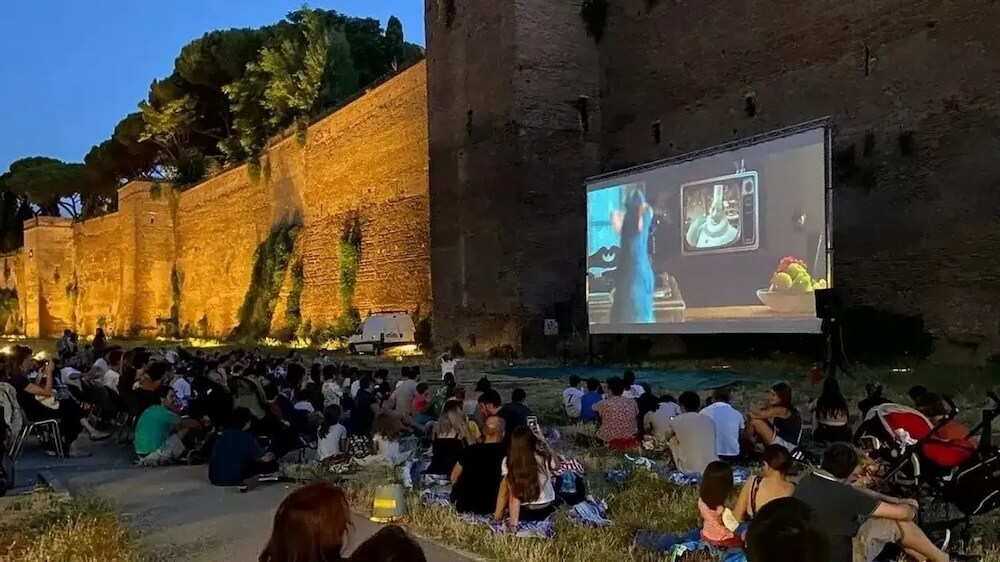 People watching a movie on a screen against the backdrop of the Aurelian Walls
