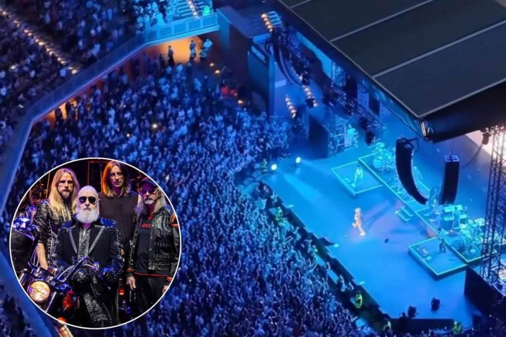 Veduta dall'alto dell’arena dell’Auditorium Parco della Musica di Roma durante un concerto notturno con il palco illuminato di blu. Nell'angolo in basso a sinistra è presente un inserto circolare in sovraimpressione che ritrae la band Judas Priest, con il cantante Rob Halford in primo piano.
