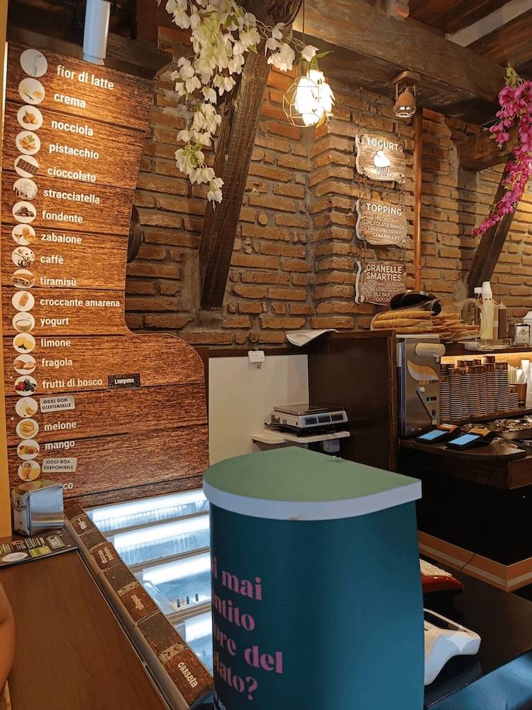 Interno rustico della gelateria italiana La Botte Gelata a Genzano con menu dei gusti e insegne decorative