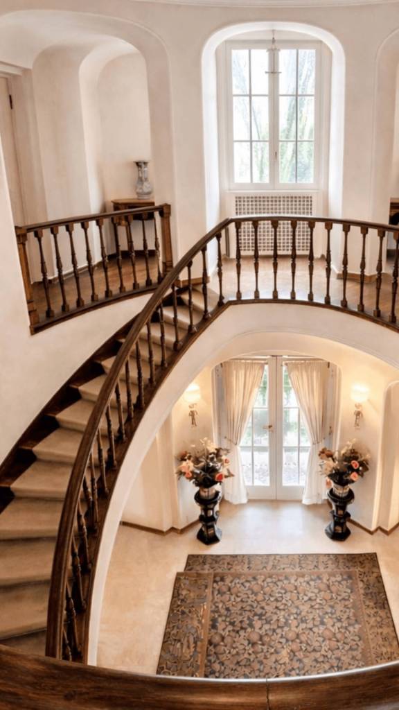 Interno di lusso della villa Gucci a Roma con scenografica scala a chiocciola in legno e vestibolo luminoso.