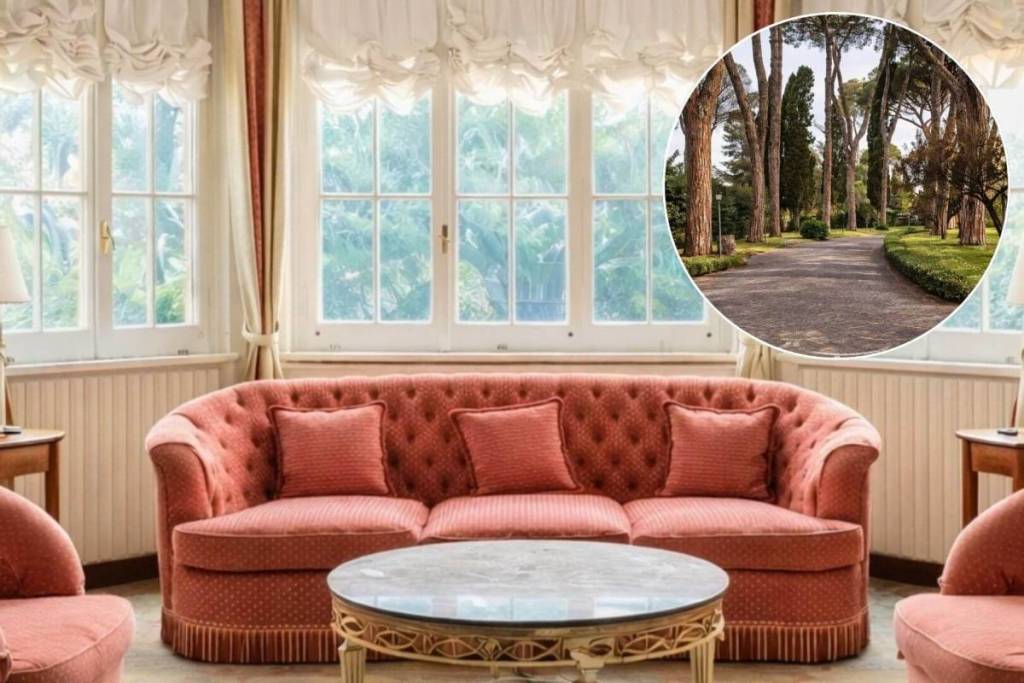 Salotto di lusso della storica villa Gucci a Roma con divano capitonné rosa antico e inserto circolare che mostra il viale alberato del parco privato