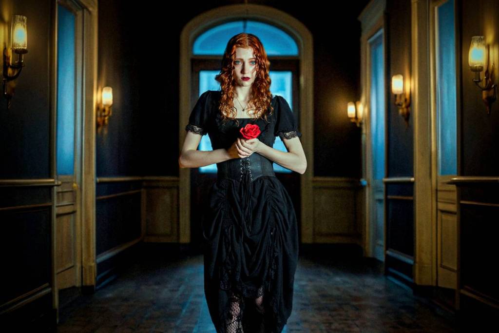 woman in dimly lit hallway holding a rose