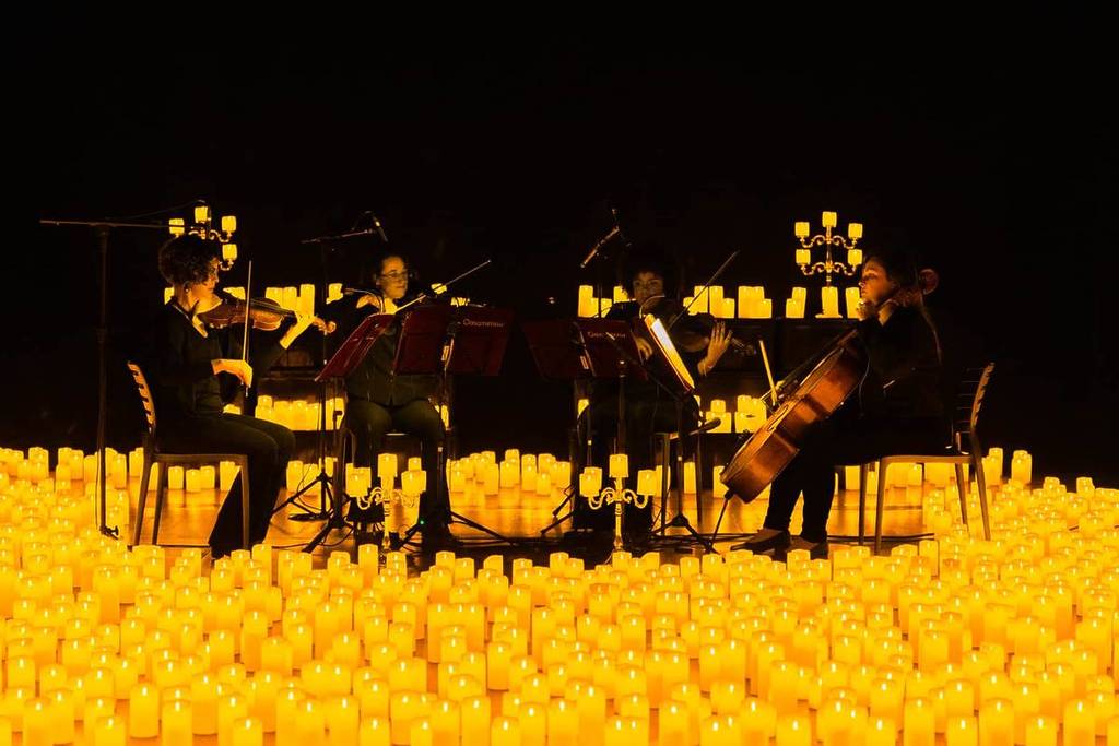 A string quartet performing amid a sea of candles