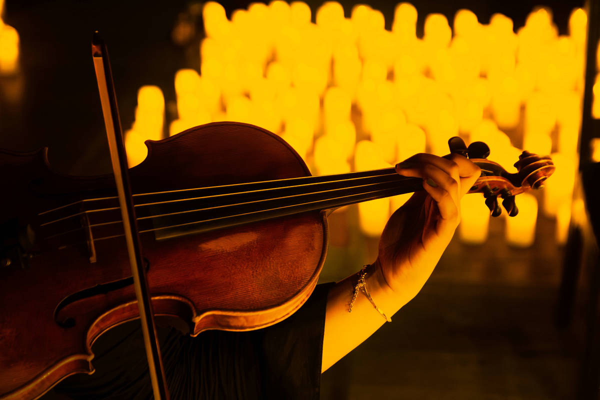 A violinist performs, surrounded by candles at a Candlelight concert.