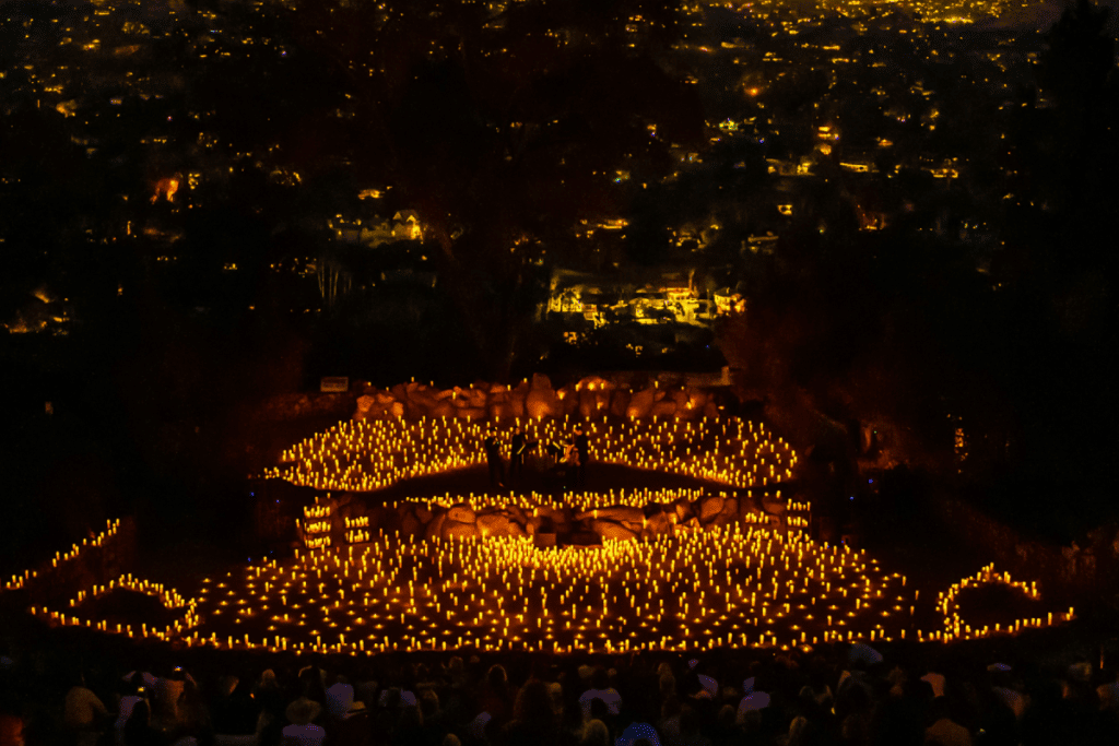 A birds eye view of Mt.Helix Park capturing a Candlelight concert taking place with candles everywhere and lights from the city visible in the background.