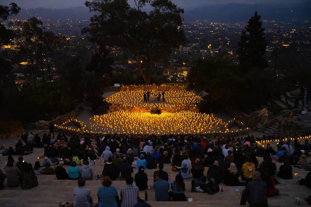 A wide shot of Mt. Helix Park venue in San Diego taken from the audience watching a string quartet perform on the stage with the setting covered entirely by candles.