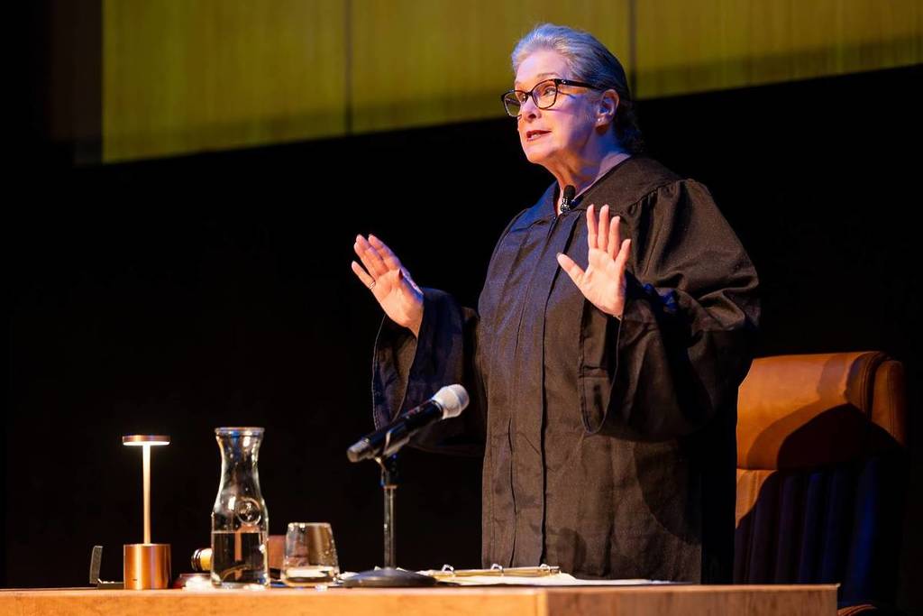 The judge raises her hands at the bench at The Jury Experience.