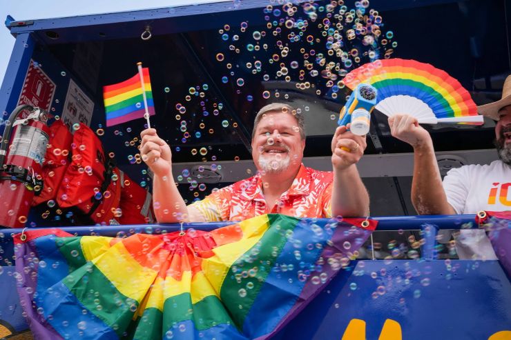man at a Pride event with bubbles and flags