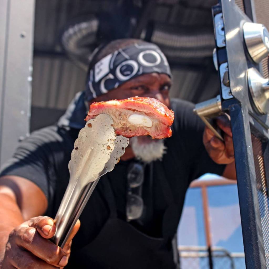 Black chef showing a piece of meat he cooked