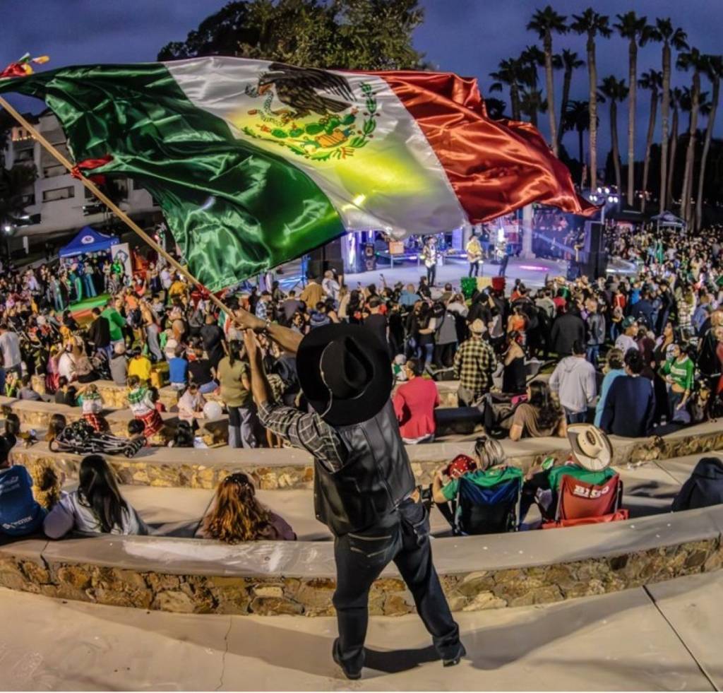 hombre con la bandera mexicana frente a la multitud en el Día de la Independencia de México