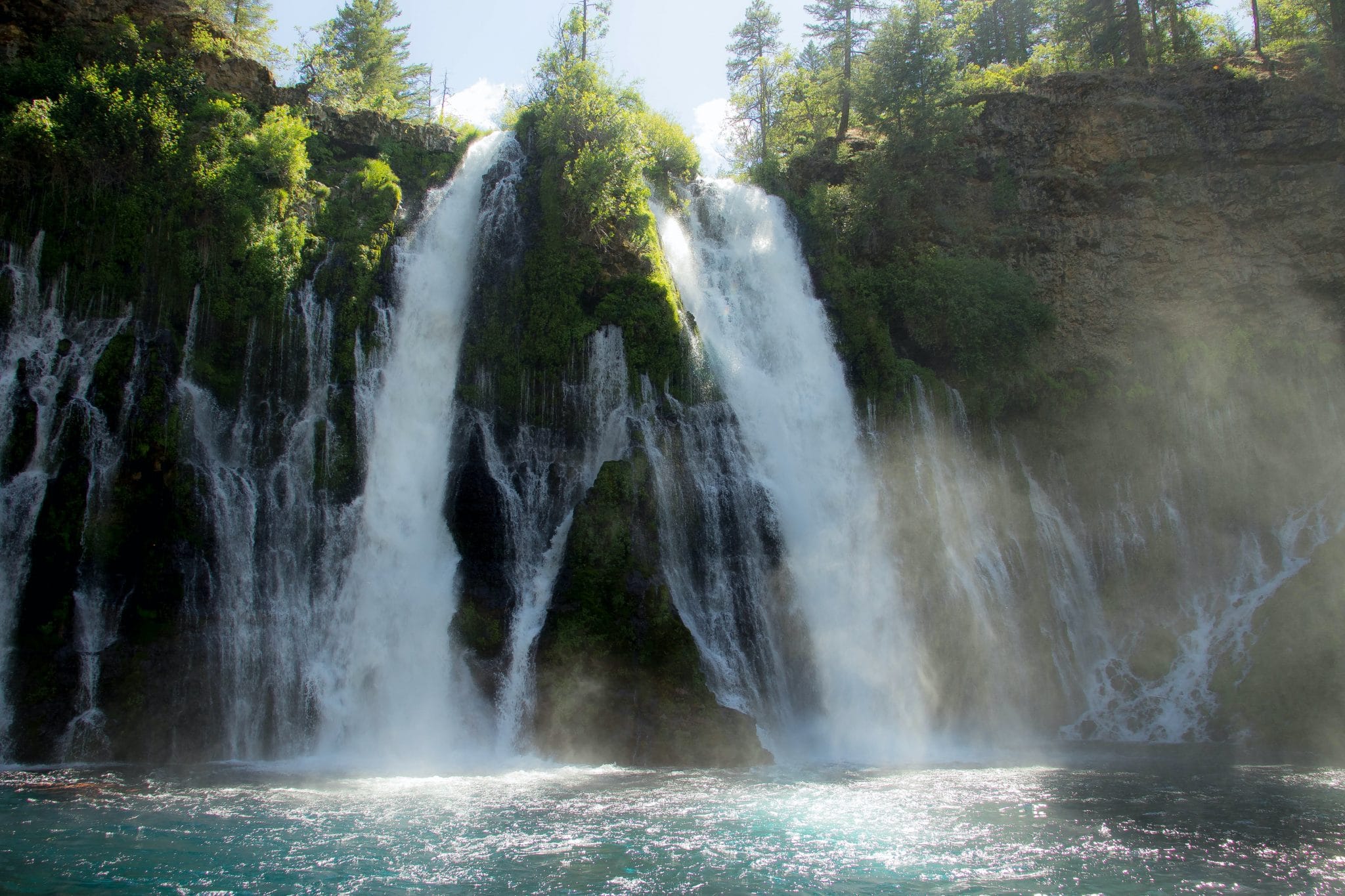 Two large waterfalls pour into a big pool of water.