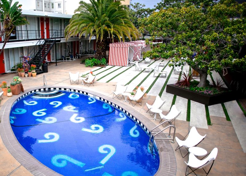 An oval pool surrounded by white beach chairs.