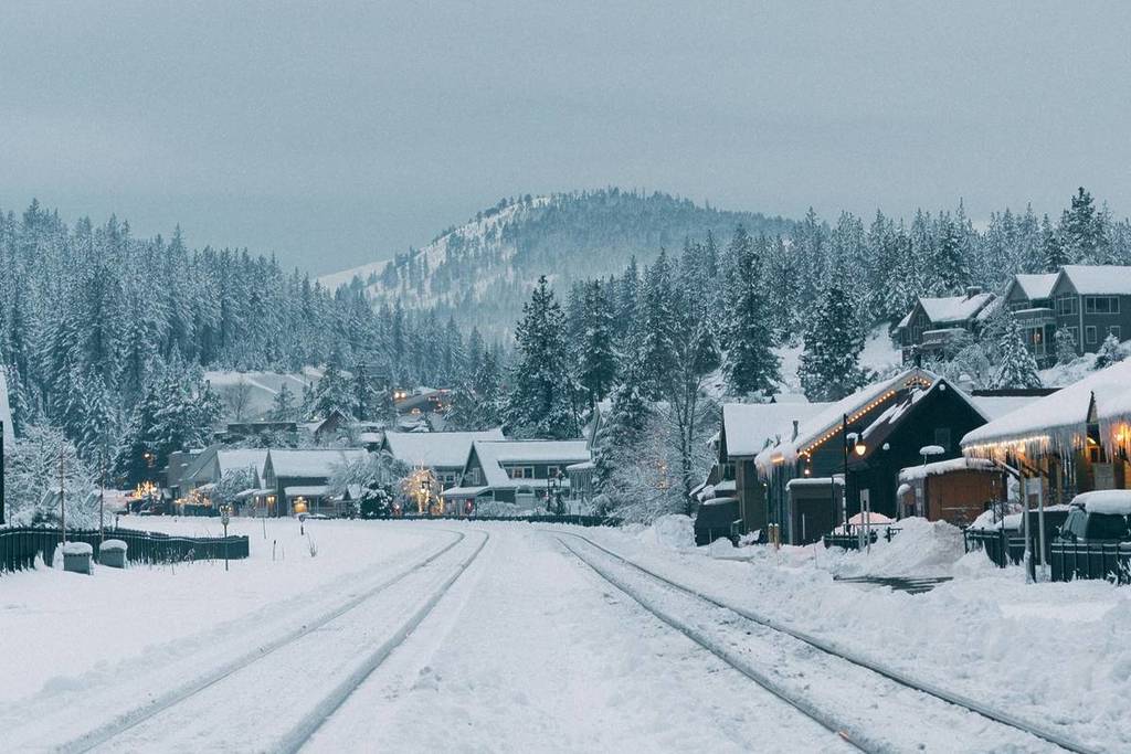 A snowy town landscape with mountains in the background.