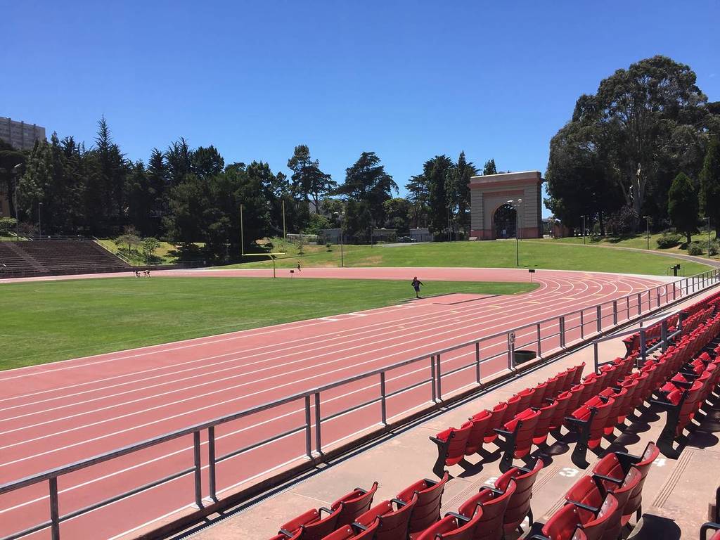 a stadium with green grass and red seats on a sunny day