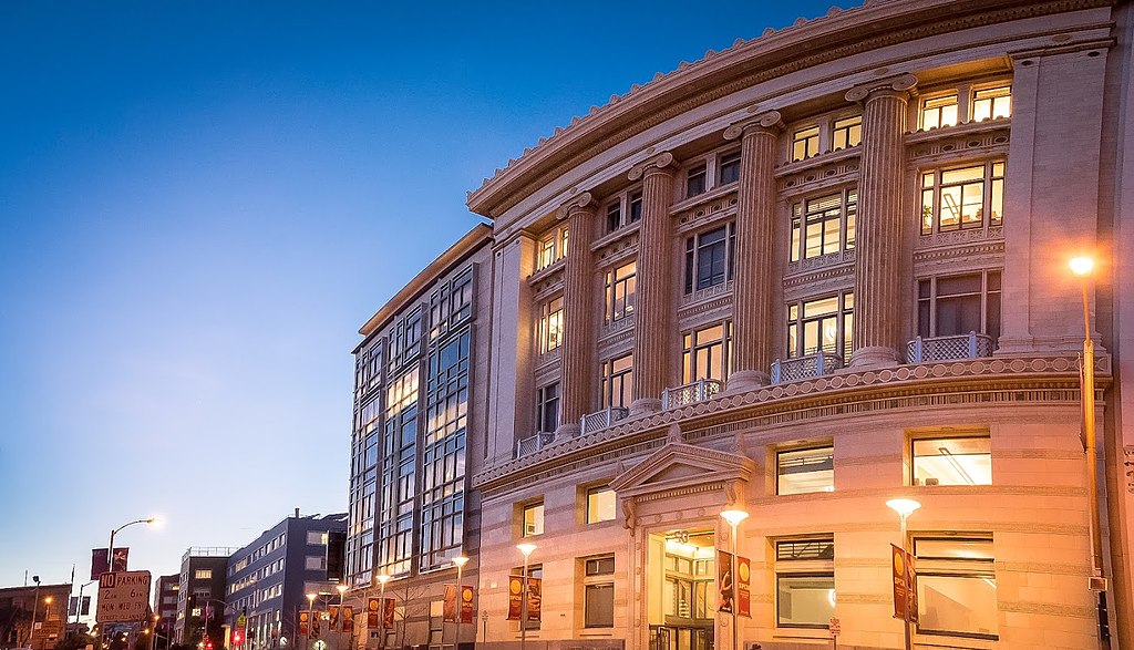 The glowing stone edifice of the San Francisco Conservatory of Music in the evening.