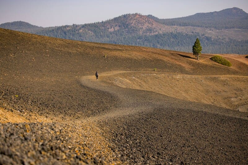 A person walks in a desolate hilly landscape at Lassen National Park.