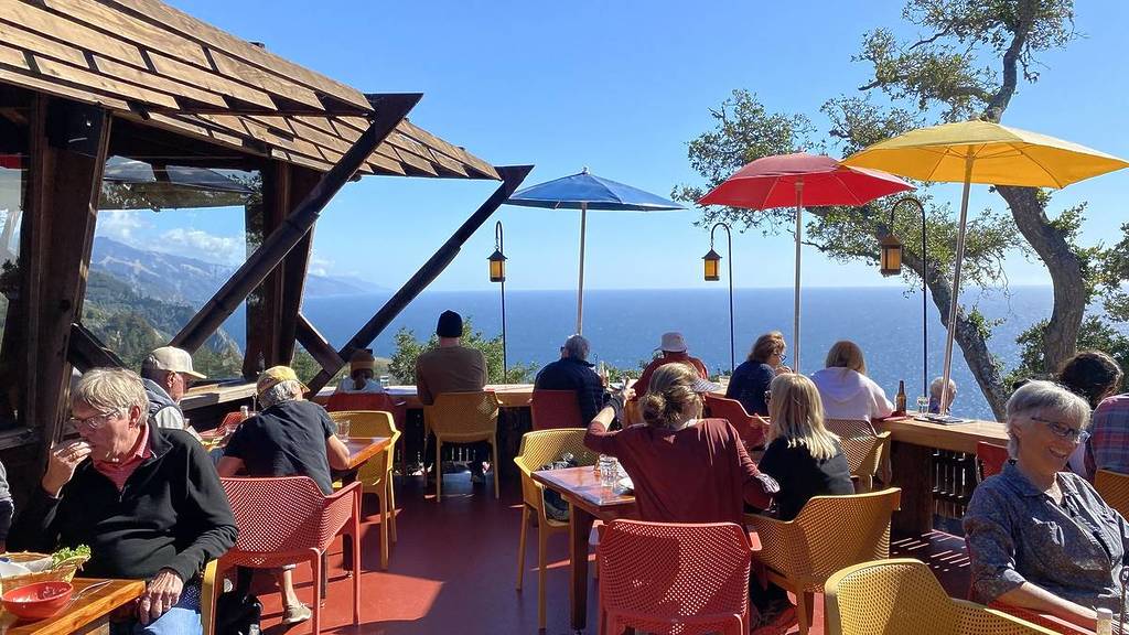 un restaurante con sillas de colores y vistas al océano