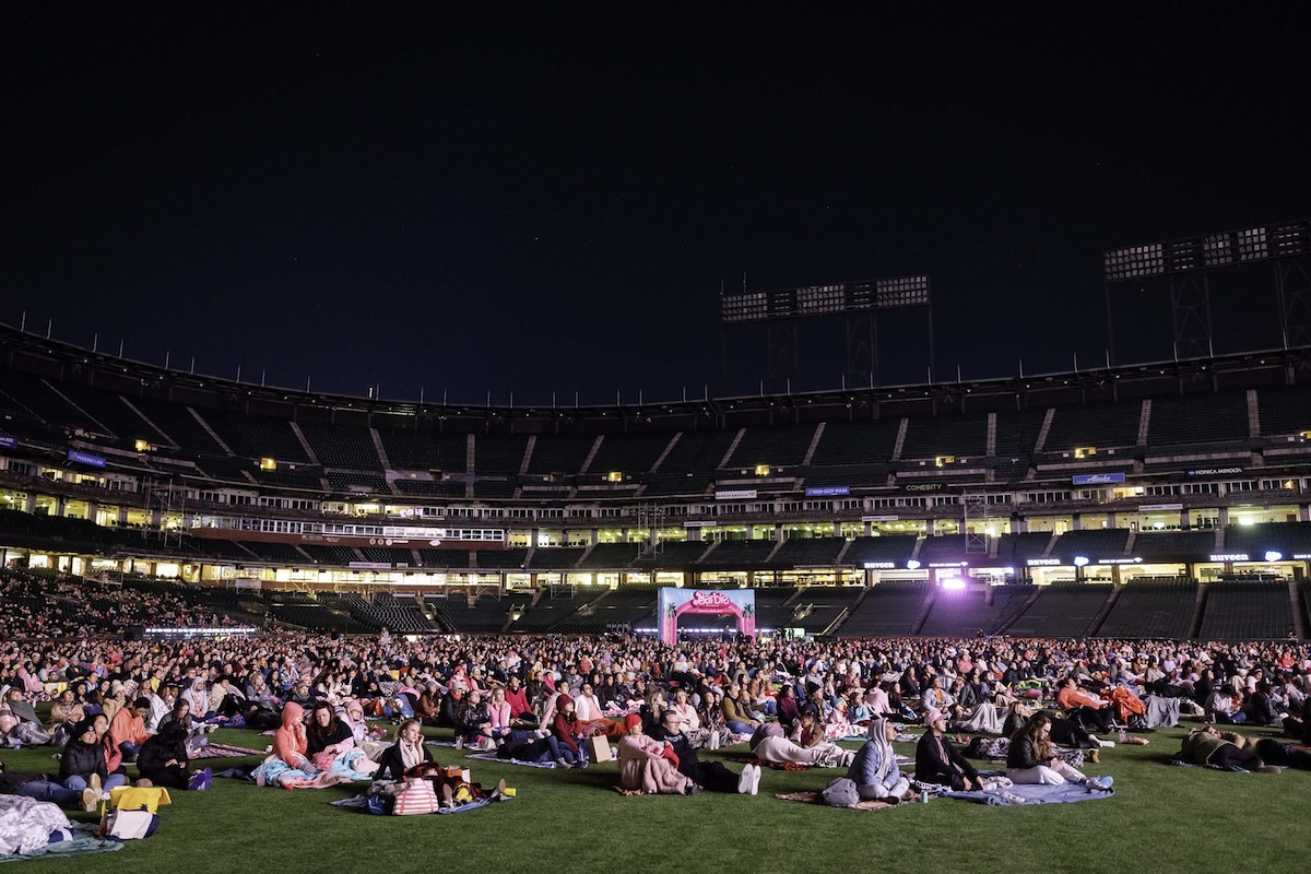 Oracle park with people sitting on the field watching a movie