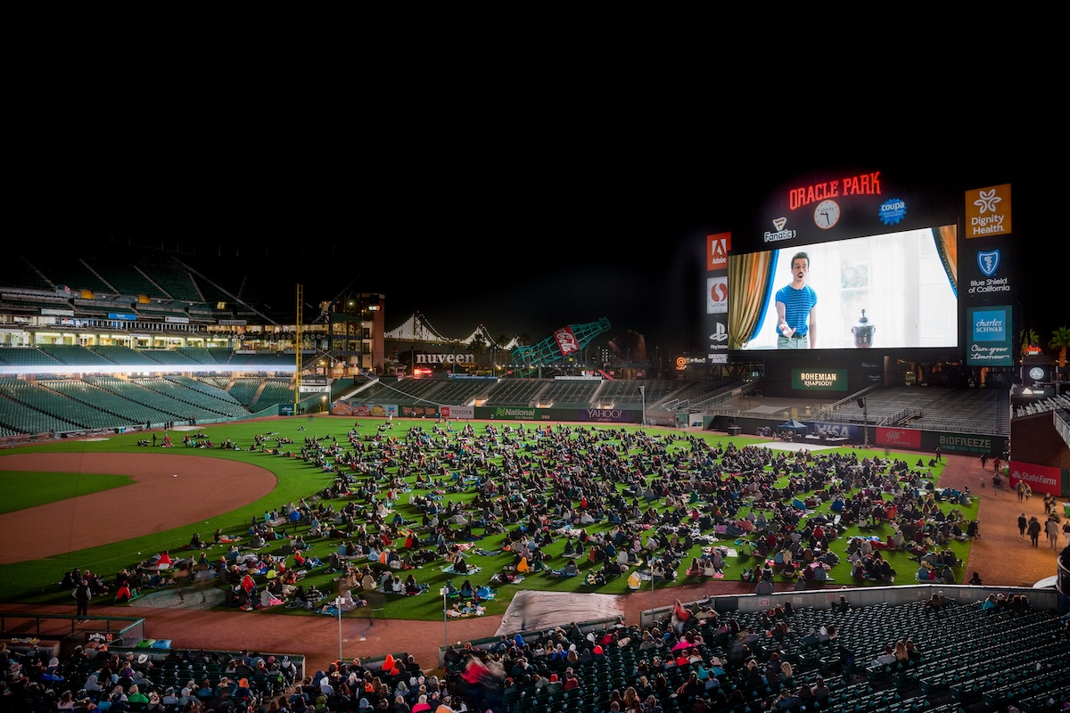 Oracle park with people sitting on the field watching a movie