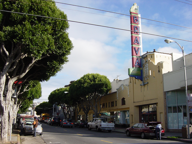 long street with blue skirs and exterior of old theater with large sign