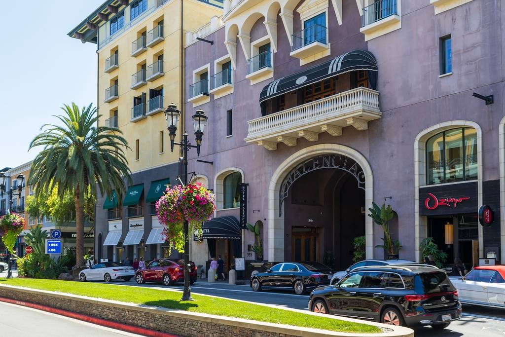 San Jose California USA - 7 15 2025: a hotel, restaurants, parked cars, palm trees, and ornate streetlights on a bright day at Santana Row Shopping Mall in San Jose California USA