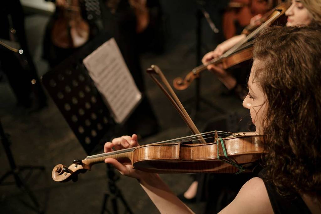 woman plays violin as part of classical music concert