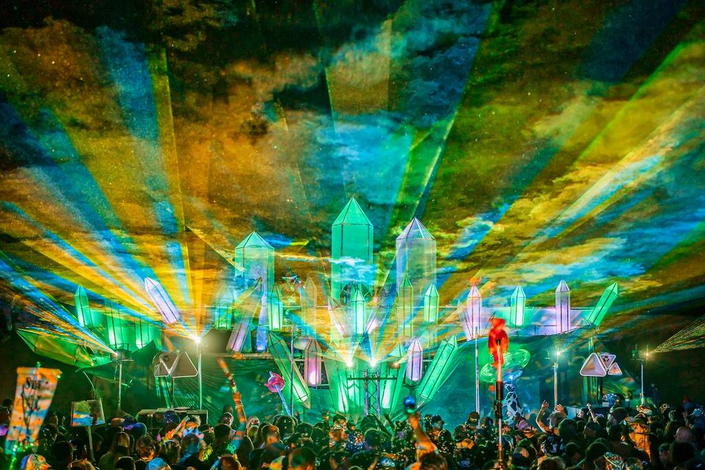 un gran escenario con luces y gente bailando en un festival de música