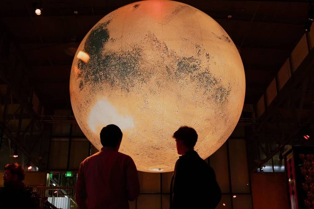 Two people in front of moon sculpture in Exploratorium space exhibition