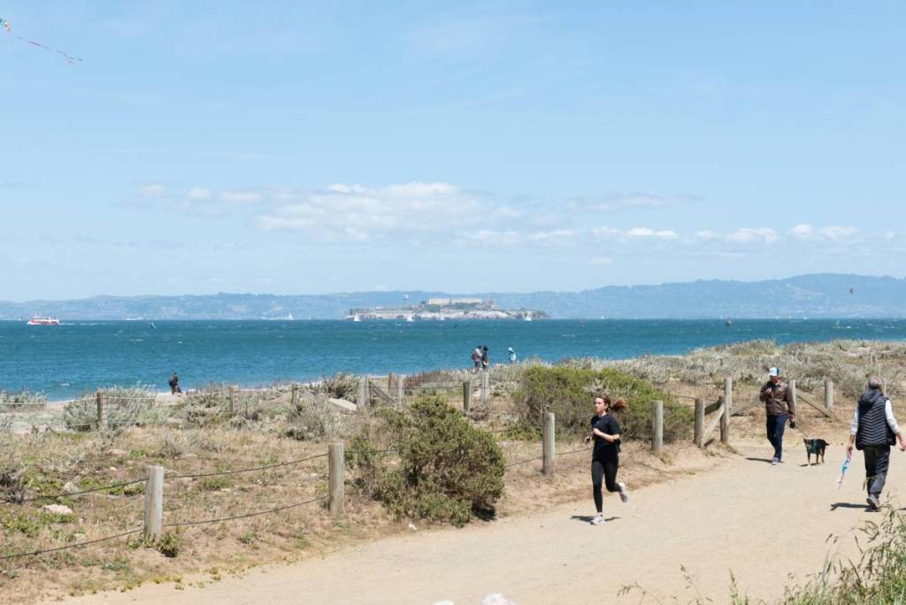 Un corredor en un sendero con Alcatraz y la bahía de San Francisco al fondo.