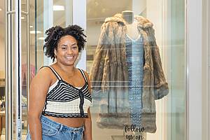 A woman poses in front of a coat at Pomp + Sway