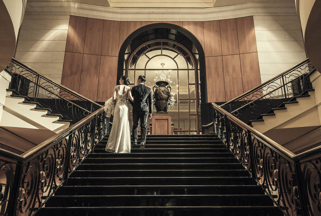 A well-dressed couple ascend the staircase at the Four Seasons Hotel in Singapore.