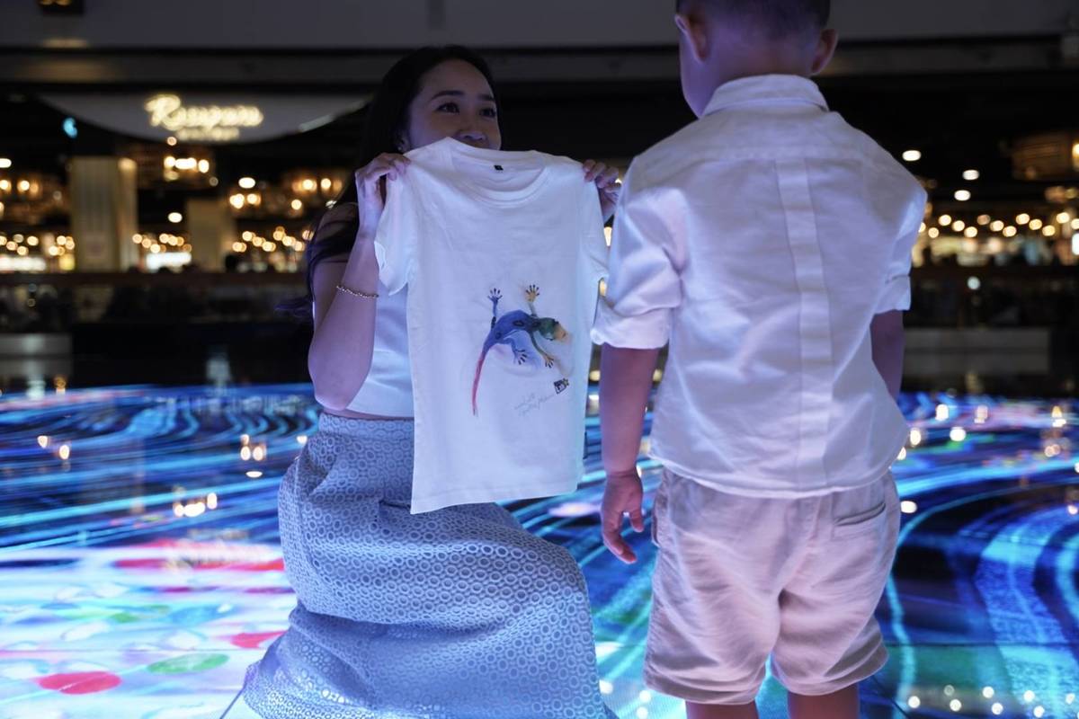 A mother proudly showing off a design on a t-shirt to her son