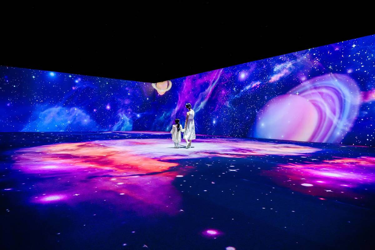 A stunning display of stars and planets surrounding a mother and daughter walking around GROUNDSEESAW