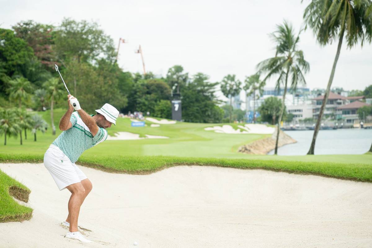 A golfer swinging in a bunker portion of Sentosa Golf Course