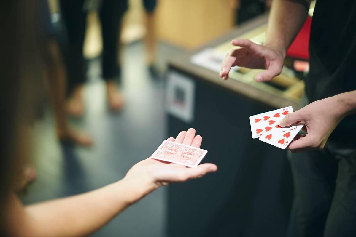 A magician performing a card trick with the help of one of Magic Attic's guests