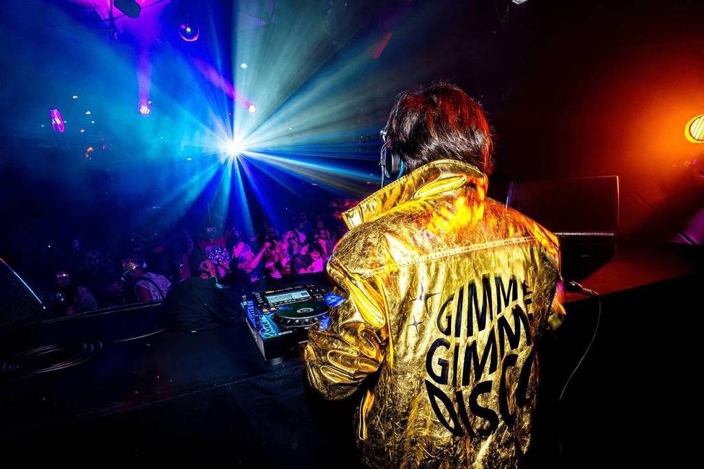 dj wears gold jacket and plays for audience at gimme gimme disco